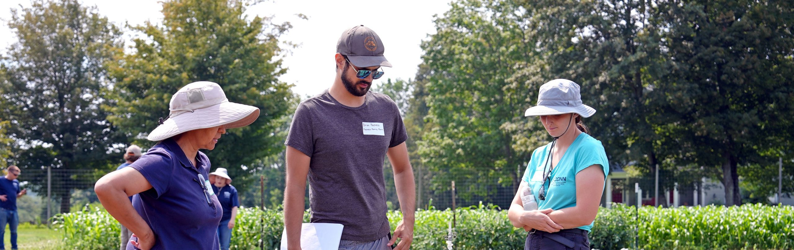 3 individuals looking down at soil at a farm