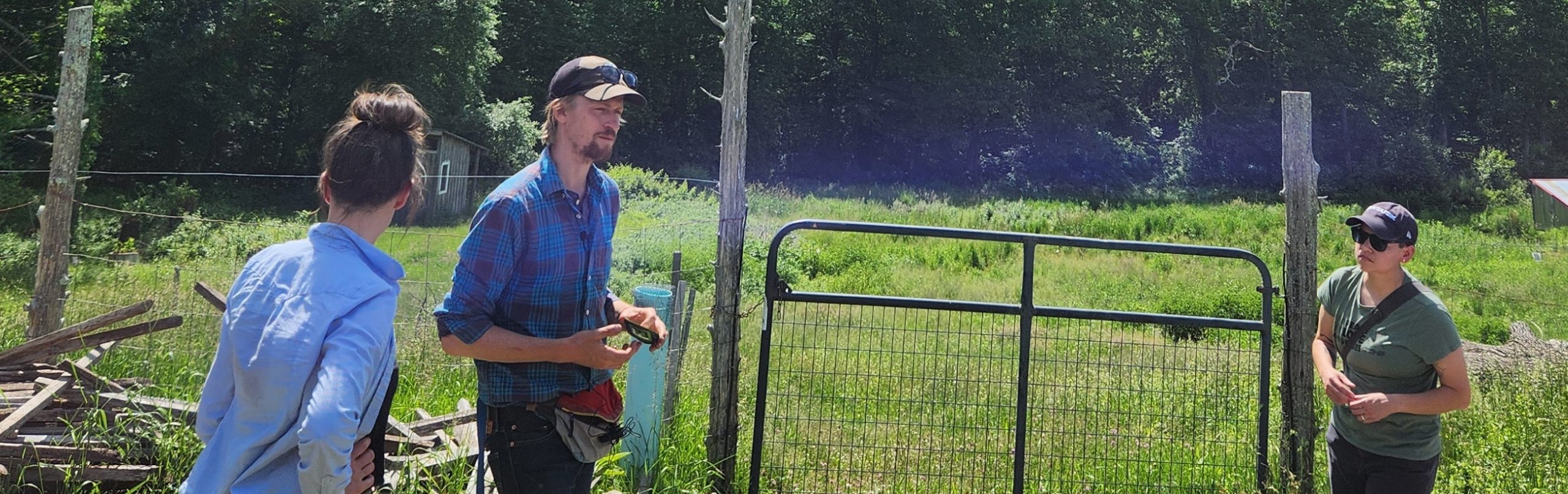 two farmers standing in front of their field talking to an extension agent